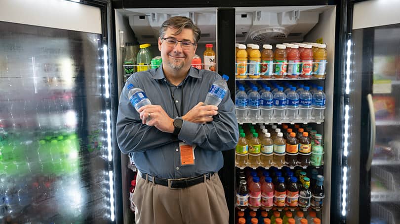 Man holding water bottles in front of coolers